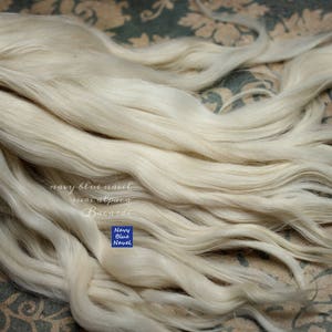 May include: A close-up of a large bundle of white, silky fibers. The fibers are arranged in a loose, flowing pattern, creating a soft and delicate texture. The text "navy blue novel" is visible in the lower right corner of the image.