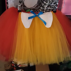 May include: A red and yellow tulle tutu with a white felt collar and a blue ribbon bow.