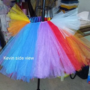 May include: A rainbow tulle tutu skirt with a white tulle overlay. The skirt is on a mannequin and the text "Kevin side view" is visible in the image.