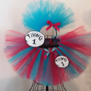 May include: A red and blue tulle tutu with two white and black signs that say "Thing 1".
