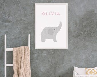 May include: A white rocking horse with a gray concrete wall in the background. A white crib with a gray and white patterned blanket and a yellow and white patterned pillow is in the background. A white ladder with a beige knitted blanket hanging on it is in the foreground. A framed print with the name "Olivia" and a gray elephant illustration is on the wall.