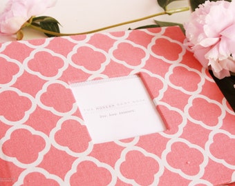 May include: A pink baby book with a white geometric pattern and a window showing the text "The Modern Baby Book - Live, Love, Treasure".