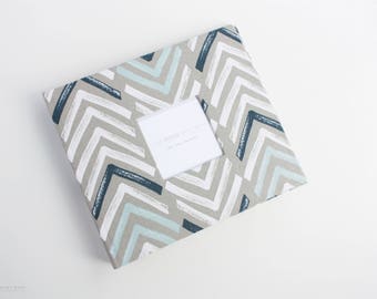 May include: A gray photo album with a blue and white chevron pattern. The album has a white insert with the text "The Modern Maker" and "The Baby Planner".