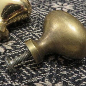 May include: Two mushroom-shaped cabinet knobs made of polished brass. Each knob features a smooth, rounded top and a cylindrical base with an attached threaded metal screw and a flat washer for secure installation on furniture or cabinetry.
