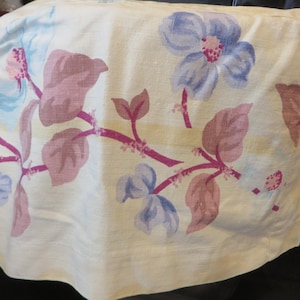 May include: A white fabric kitchen appliance cover with a floral pattern. The pattern features pink, blue, and purple flowers with green leaves.
