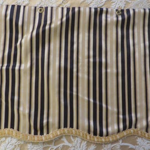 May include: A striped curtain panel with a scalloped bottom edge. The curtain is made of a beige and black striped fabric.