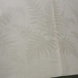 May include: A white fabric featuring a subtle, tonal jacquard pattern of fern leaves. The design is woven directly into the material, creating a soft, monochromatic texture with repeating botanical motifs across the surface of the textile.