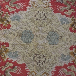 Peut inclure: Textile or tissu orné d'un motif répété de dragons, de fleurs et de nuages tourbillonnants. Le design présente des couleurs rouge, crème et marron. L'ensemble évoque l'art asiatique traditionnel.