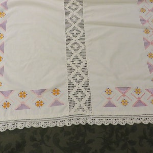 May include: White tablecloth with a crocheted border and embroidered floral design in pink, purple, and orange.