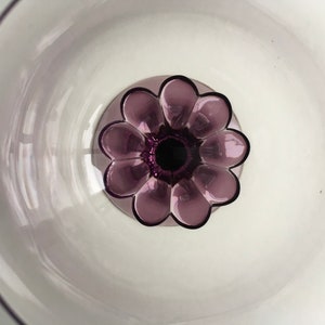 May include: A clear glass bowl with a purple flower-shaped base. The bowl is empty and the flower base has a dark purple centre.