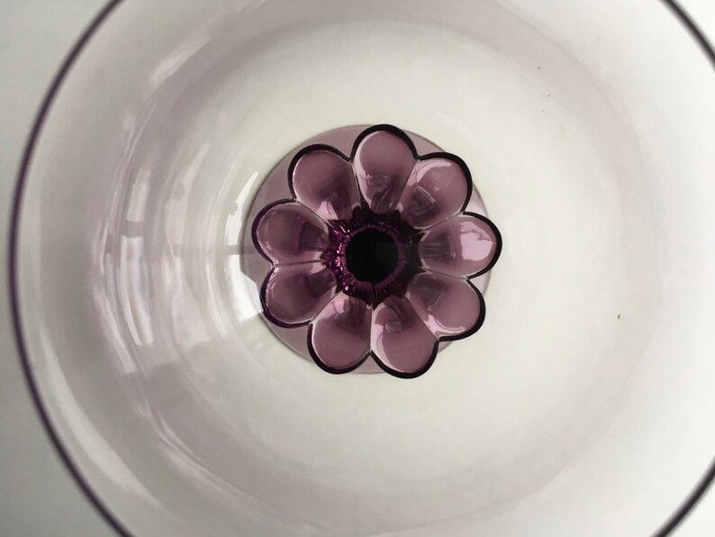 May include: A clear glass bowl with a purple flower-shaped base. The bowl is empty and the flower base has a dark purple centre.