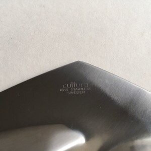 Pu&ograve; includere: Primo piano del fondo di un utensile da portata argentato con il testo "cultura 18-8 stainless SWEDEN" inciso sulla superficie.