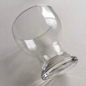 May include: A clear glass goblet with a wide bowl and a thick, rounded base.