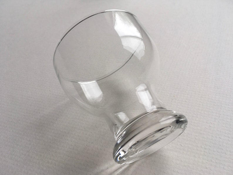 May include: A clear glass goblet with a wide bowl and a thick, rounded base.
