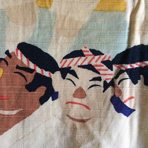 May include: Three cartoon faces with black hair and red and white striped headbands. The faces are brown, tan, and white with black eyes and red mouths. The background is a light beige fabric.
