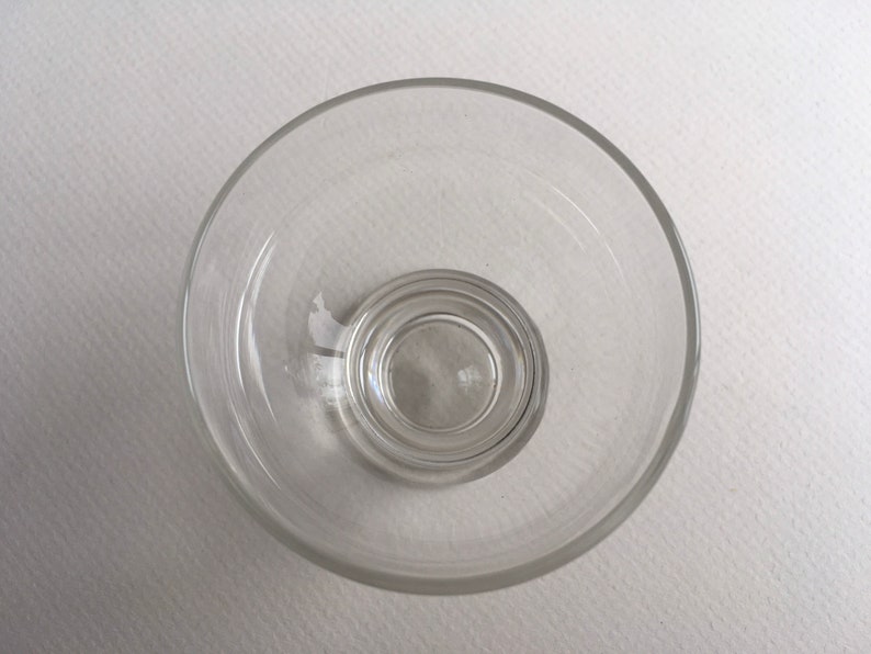 May include: A clear glass bowl with a smaller, concentric bowl inside. The bowl is empty and appears to be made of thick glass.