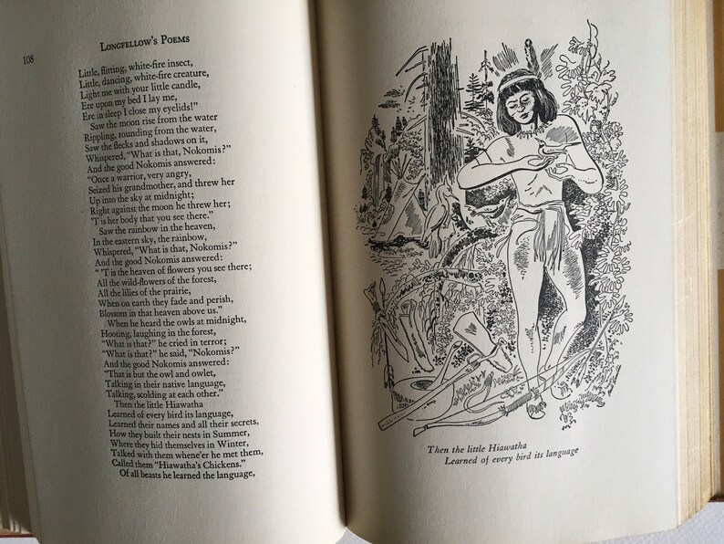 May include: Black and white illustration of a Native American person standing in a forest. The person is holding a small object in their hands. The text "Then the little Hiawatha Learned of every bird its language" is at the bottom of the image.