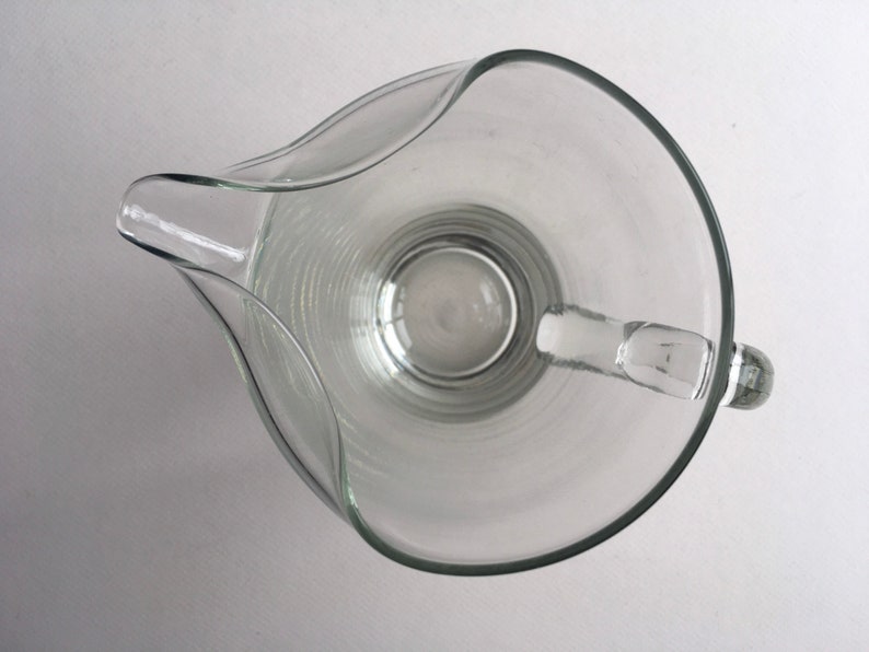 May include: A clear glass pitcher with a wide mouth and a handle. The pitcher has a textured, ribbed design.