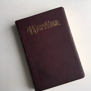 May include: A dark brown leather-bound book with the title "WHITTIER" embossed in gold lettering.