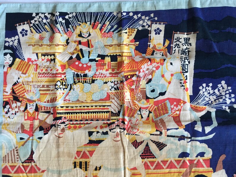 May include: A colourful Japanese textile depicting a scene of samurai warriors on horseback. The textile is blue, white, red, yellow and black. The text on the textile reads "Black Horse Regiment".