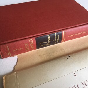 May include: A red hardcover book titled "Best Loved Poems of Henry Wadsworth Longfellow". The book is open and the spine is visible.