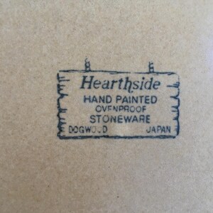 May include: A black and white image of a sign that reads "Hearthside Hand Painted Ovenproof Stoneware Dogwood Japan".