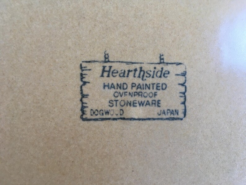 May include: A black and white image of a sign that reads "Hearthside Hand Painted Ovenproof Stoneware Dogwood Japan".