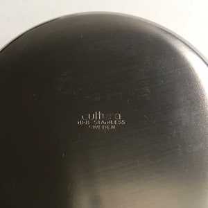 Pu&ograve; includere: Il fondo di una ciotola di metallo argentata con il testo "cultura 18-8 stainless SWEDEN" inciso sulla superficie.