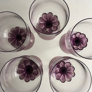 May include: Set of five purple glass wine glasses with a flower design on the base.
