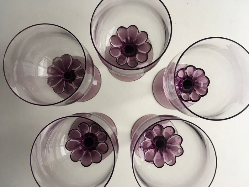 May include: Set of five purple glass wine glasses with a flower design on the base.
