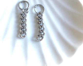 May include: A pair of silver-toned hoop earrings, each featuring a dangling curb chain link attachment. The earrings are constructed from polished metal links that hang vertically from a circular hoop closure, creating a simple, metallic design.