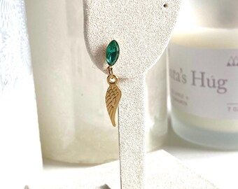 May include: Gold dangle earrings with a green gemstone and a gold wing charm.