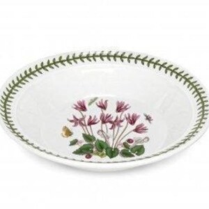 May include: A white ceramic bowl with a green border and a floral design featuring pink cyclamen flowers. The bowl is perfect for serving soup, salad, or pasta.