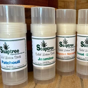 May include: Four clear plastic tubes containing solid lotion sticks. Each tube has a white label with green text and a green plant illustration. The labels read "Soaptree Solid Lotion Stick" and list the scent of each lotion: Patchouli, Jasmine, Bergamot Nectarine, and Great Outdoors.