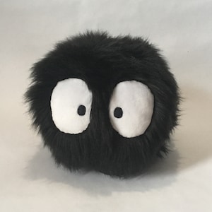 May include: Black plush toy with large white eyes. The toy is round and fuzzy.