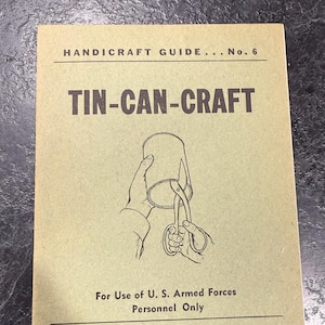 May include: A vintage handbook titled "TIN-CAN-CRAFT" with the text "HANDICRAFT GUIDE... No. 6" at the top. The cover features an illustration of a hand holding a tin can and using scissors. Published for U.S. Armed Forces personnel.