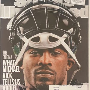 Könnte beinhalten: Sports Illustrated-Magazin-Cover mit Michael Vick. Das Cover enthält den Text "Jimmie Johnson ist der größte Fahrer aller Zeiten, ja" und "Das Rätsel, was Michael Vick uns über uns selbst erzählt". Das Cover enthält auch ein Foto von Michael Vick mit Helm.