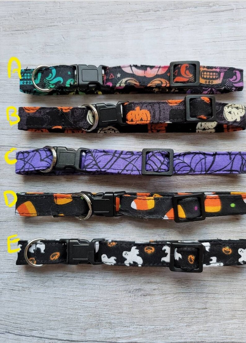 May include: Five Halloween-themed dog collars with black plastic buckles and metal D-rings. The collars feature various patterns, including skulls, pumpkins, spiderwebs, candy corn, and ghosts. Each collar is a different design, perfect for the spooky season.