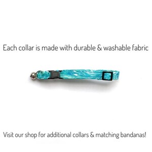 May include: A teal and white patterned cat collar with a black buckle and a silver bell. The text "Each collar is made with durable & washable fabric" is above the collar. The text "Visit our shop for additional collars & matching bandanas!" is below.