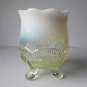 May include: A white and yellow glass bowl with a scalloped rim and three legs. The bowl has a gradient of blue to white to yellow.