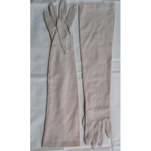 Peut inclure: Une paire de gants longs de style opéra dans une couleur beige clair unie. Les gants présentent une finition lisse et mate, s'étendant bien au-delà du poignet pour couvrir l'avant-bras. Chaque gant possède cinq doigts et un design simple.