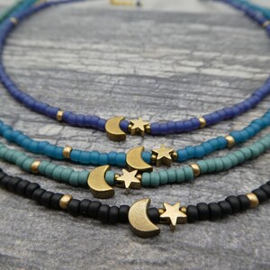 May include: Four layered necklaces with a crescent moon and star charm. The necklaces are made of small beads in shades of blue, teal, and black.