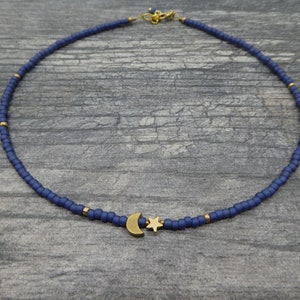 May include: A delicate blue beaded necklace with a gold crescent moon and star charm.