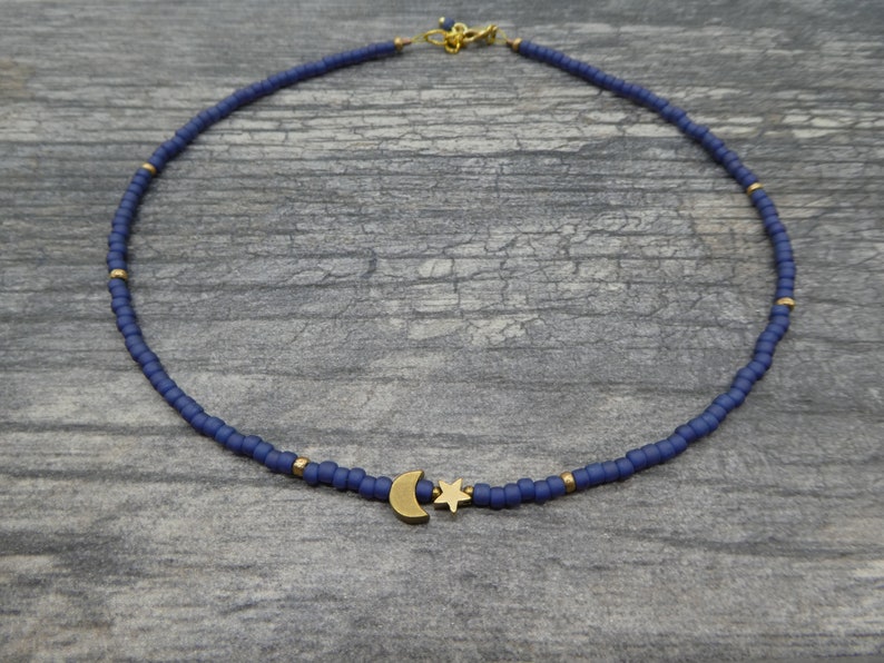 May include: A delicate blue beaded necklace with a gold crescent moon and star charm.