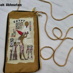 May include: A brown fabric pouch with a zipper closure and a gold chain strap. The pouch features an embroidered image of an Egyptian pharaoh with hieroglyphics and the word "EGYPT".