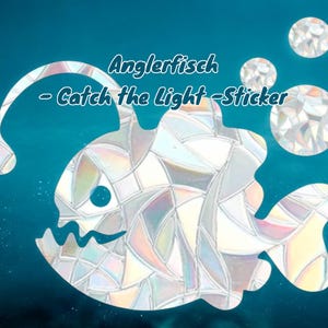 Puede incluir: Una silueta blanca de un pez pescador con un patrón de vitral. El texto "Anglerfisch - Catch the Light - Sticker" está por encima del pez.