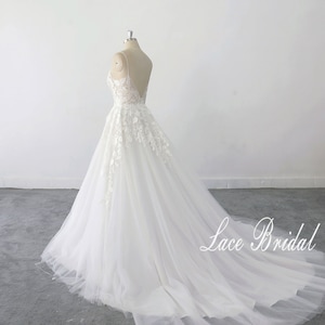 May include: A white lace wedding dress with a sweetheart neckline and a tulle skirt. The dress has a long train and is displayed on a mannequin against a white background. The text 'Lace Bridal' is visible in the bottom right corner of the image.
