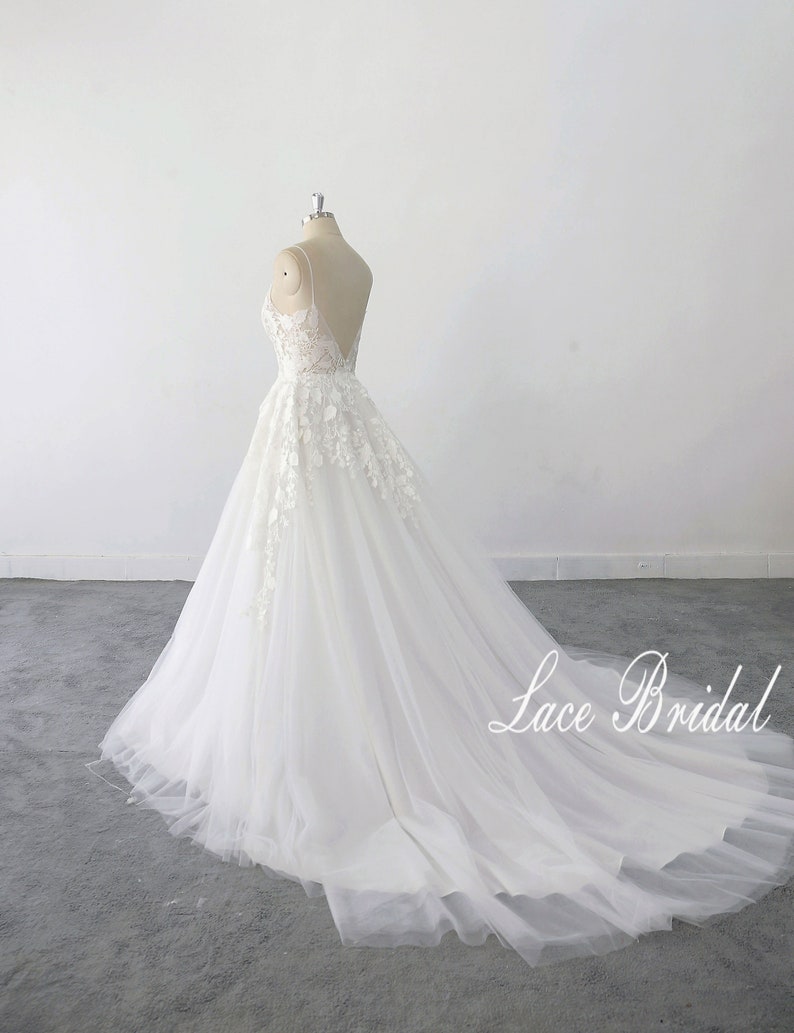 May include: A white lace wedding dress with a sweetheart neckline and a tulle skirt. The dress has a long train and is displayed on a mannequin against a white background. The text 'Lace Bridal' is visible in the bottom right corner of the image.
