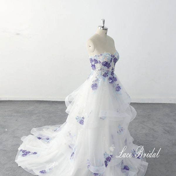 Vestido de noiva tomara que caia de renda com aplicações de rosas roxas e babados em camadas.