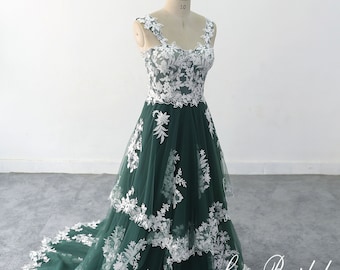 May include: A green tulle wedding dress with white lace detailing and a layered skirt. The dress has a sweetheart neckline and a fitted bodice. The dress is on a mannequin and the text "Lace Bridal" is visible in the bottom right corner of the image.